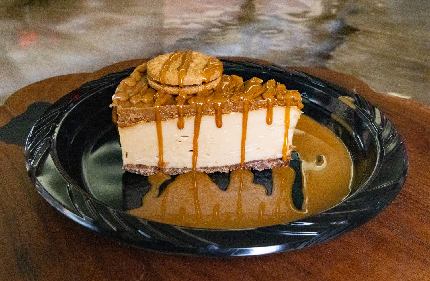A slice of caramel drizzle cheesecake on a black plate at Cornerstone Café